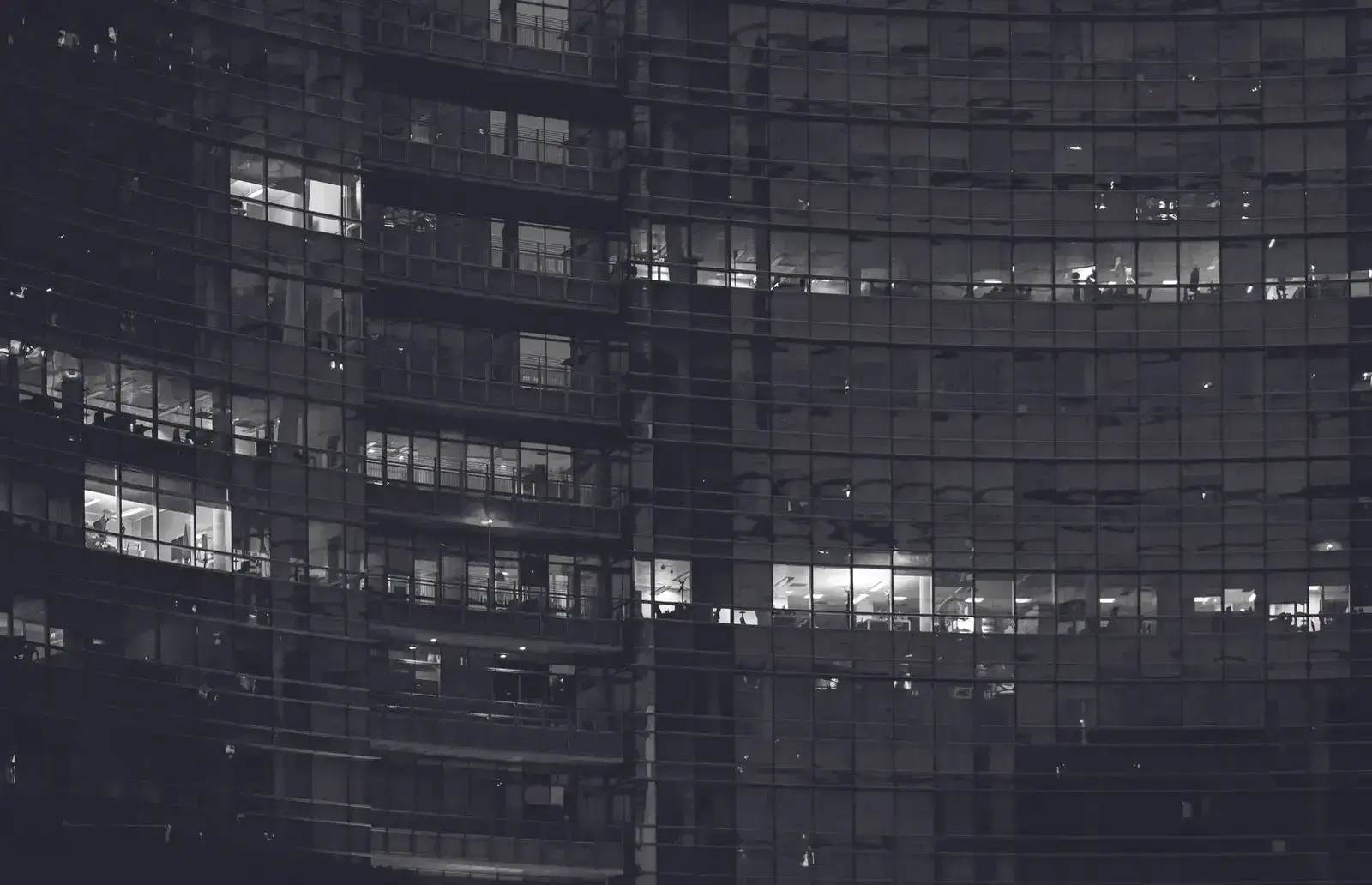 Fachada de un edificio corporativo de noche, con ventanas iluminadas